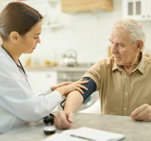 Attentive medic preparing to measure elderly man blood pressure