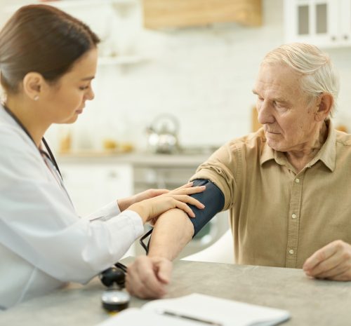 Attentive medic preparing to measure elderly man blood pressure Attentive medic preparing to measure elderly man blood pressure